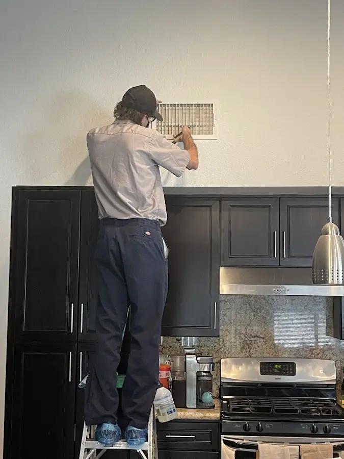 Technician inspecting an air vent during HVAC service in Spring Valley